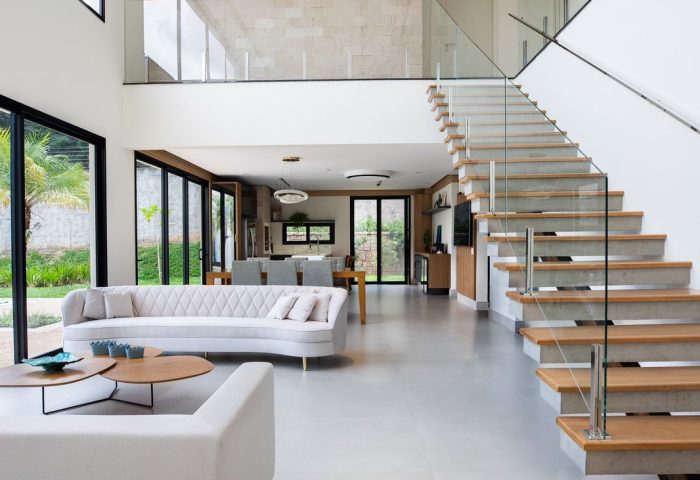 Escada de madeira com corrimão de vidro e sala em branco